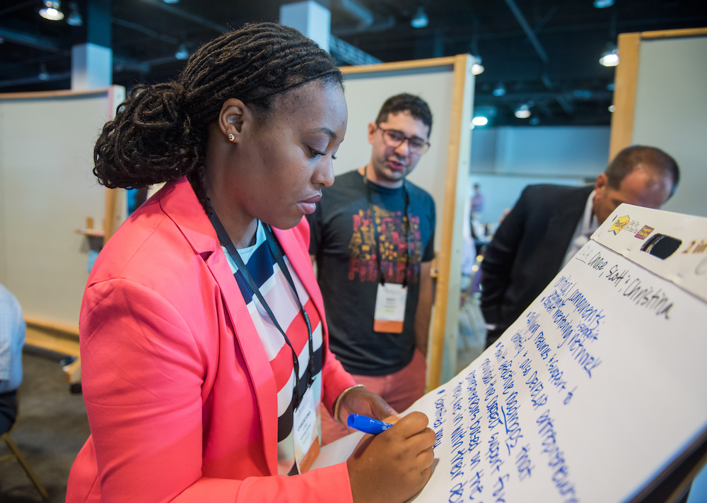 A participant adding ideas to a collaborative Summit wall